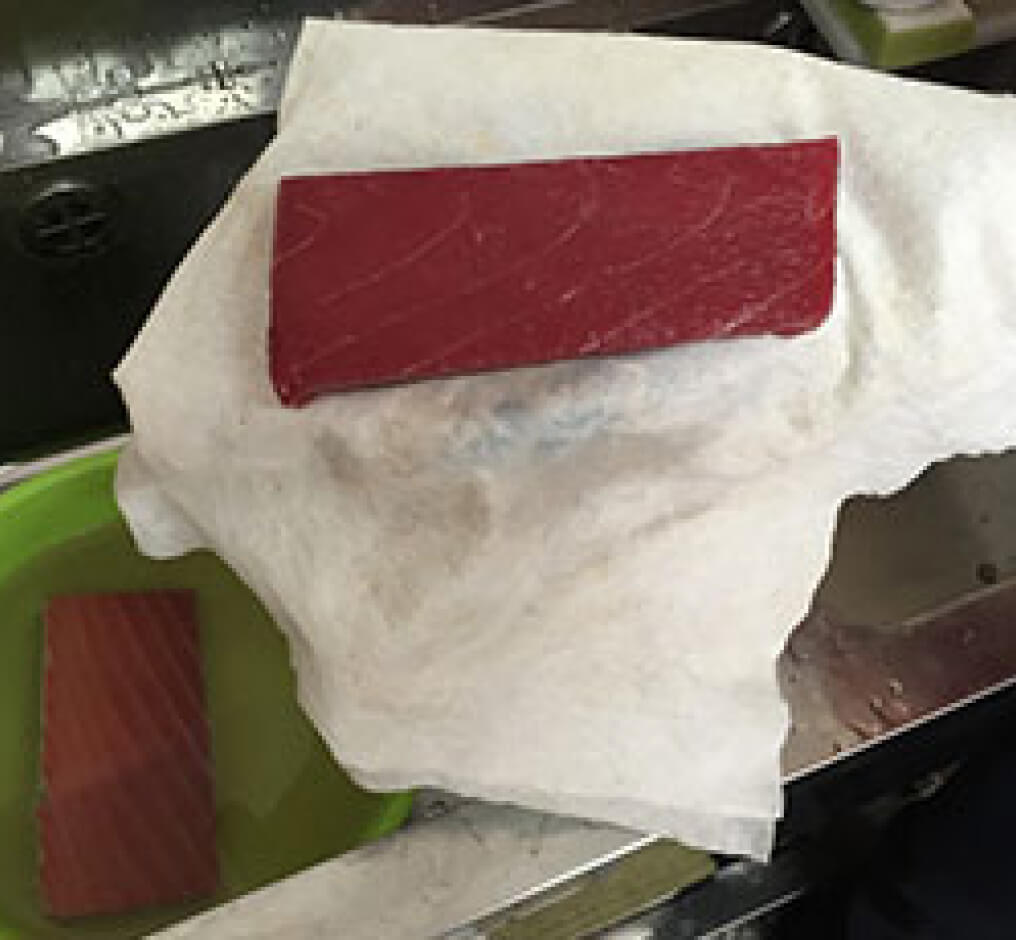 まぐろの柵の水分をキッチンペーパーで拭き取っている