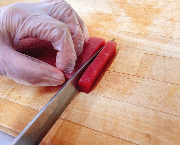 まぐろの柵を包丁で切っている